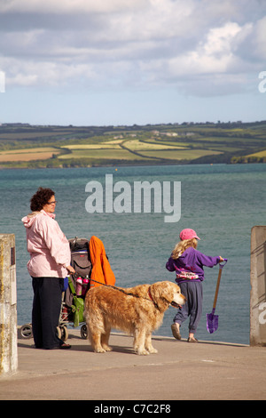 Mutter und Tochter mit Hund am Wasser in Padstow mit Rock in der Ferne in Camel Estuary, Padstow, Cornwall UK im Mai Stockfoto