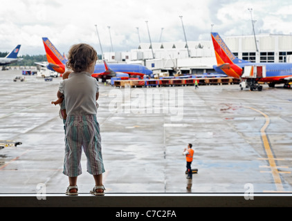 Mädchen mit Puppe beobachten Flugzeuge am Flughafen, Sea-Tac, Seattle, Washington, USA Stockfoto