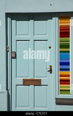 Graublaue Tür mit farbenfrohen Streifen aus horizontalen Streifen an der Seite in Padstow, Cornwall, Großbritannien, im Mai Stockfoto