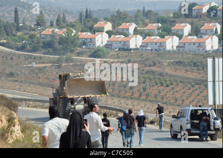 Eine unterdrückte Demonstration von den israelischen Streitkräften in den palästinensischen Dorf Nabi später versucht eine Planierraupe, die Straße zu überqueren. Stockfoto