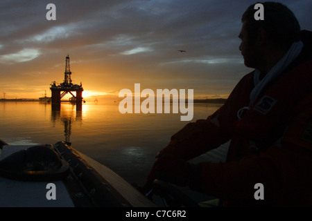 Öl-Bohr-Plattform, mit der aufgehenden Sonne hinter sich, in den Cromarty Firth, Schottland in Großbritannien. Stockfoto