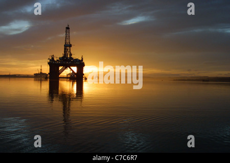 Öl-Bohr-Plattform, mit der aufgehenden Sonne hinter sich, in den Cromarty Firth, Schottland in Großbritannien. Stockfoto