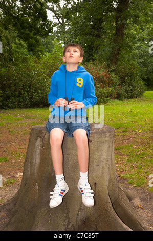 Ein elf Jahre alter Junge Vogelbeobachtung mit dem Fernglas in Fairhaven Garten, Wald und Wasser im Süden Walsham, Norfolk, Großbritannien Stockfoto