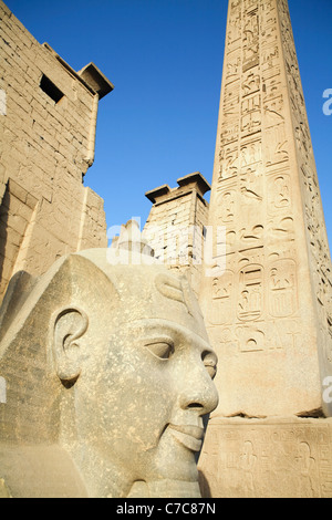 Den Kopf aus der kolossale sitzende Statue von Ramses II und der Obelisk am ersten Pylon der Luxor-Tempel, Luxor, Ägypten Stockfoto