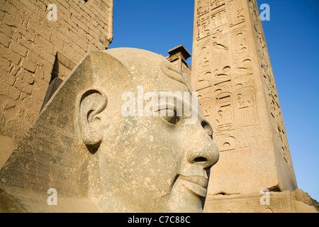 Den Kopf aus der kolossale sitzende Statue von Ramses II und der Obelisk am ersten Pylon der Luxor-Tempel, Luxor, Ägypten Stockfoto