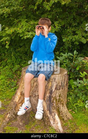 Ein elf Jahre alter Junge Vogelbeobachtung mit dem Fernglas in Fairhaven Garten, Wald und Wasser im Süden Walsham, Norfolk, Großbritannien Stockfoto