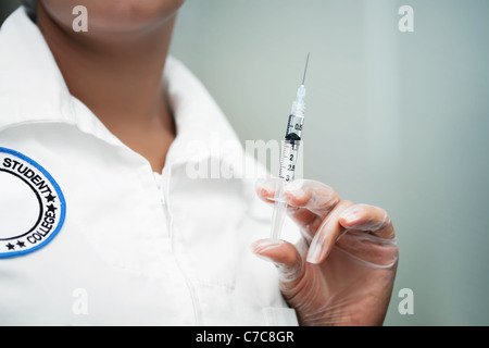 Weibliche Krankenschwesterschülerin hält eine Spritze und tragen eine generische Abzeichen Stockfoto