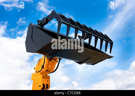 Gelbe Hydraulikbagger schwarze Grab Eimer isoliert gegen blauen Himmel Stockfoto