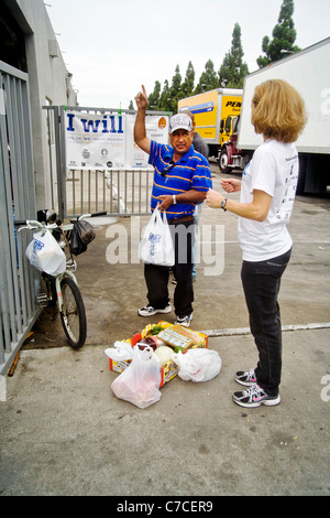 Ein afrikanischer amerikanischer Mann spricht mit freiwilliger während Verpackung gespendet Essen bei einer Charity-Verteilung in Santa Ana, Kalifornien. Stockfoto