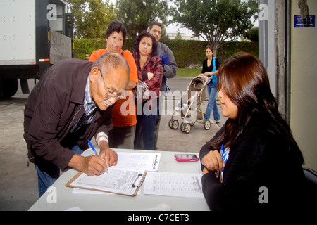 Hispanische Menschen unterschiedlichen Alters registrieren Sie sich kostenlos Lebensmittel an eine Wohltätigkeitsorganisation Lager Distribution in Santa Ana, Kalifornien. Stockfoto