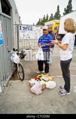 Ein afrikanischer amerikanischer Mann spricht mit freiwilliger während Verpackung gespendet Essen bei einer Charity-Verteilung in Santa Ana, Kalifornien. Stockfoto