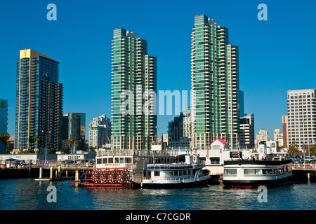 Ausflugsschiffe entlang der Uferpromenade in der Innenstadt von San Diego, Kalifornien mit Hochhäusern im Hintergrund Stockfoto