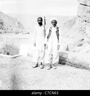Zwei Stammesangehörigen oder Pashtuns, einer bewaffnet mit Gewehr, stehend auf den Bolan-Pass, Pakistan. In den 1950er Jahren von J. Allan Bargeld genommen. Stockfoto