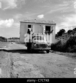 Geschichtsbild from1950s von J. Allan Cash, einen LKW mit einem Mobilheim mit Menschen, auf einer staubigen Straße in Antigua. Stockfoto