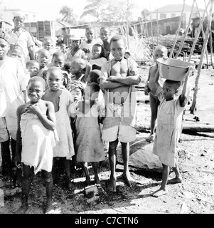Nigeria, 1950er Jahre, eine Gruppe von aufgeregt nigerischen Dorfkindern schaut auf die Kamera in diesem historischen Foto von J Allan Cash. Stockfoto
