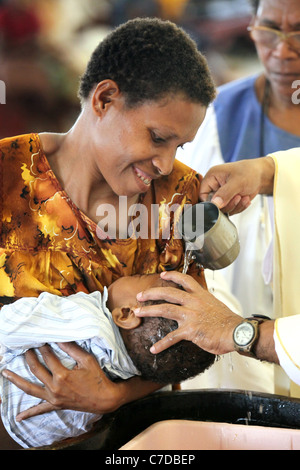 Baby in den Armen der Mutter getauft (getauft, genannt) von einem katholischen Priester. Kiunga, Papua-Neuguinea Stockfoto