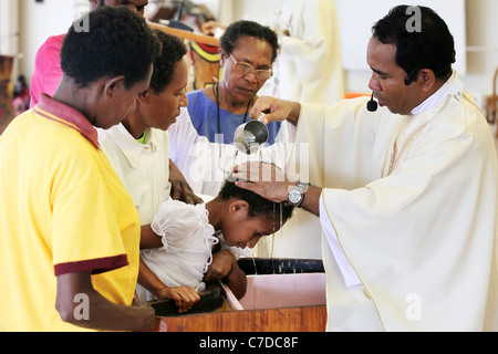 Baby in den Armen der Mutter getauft (getauft, genannt) von einem katholischen Priester. Kiunga, Papua-Neuguinea Stockfoto