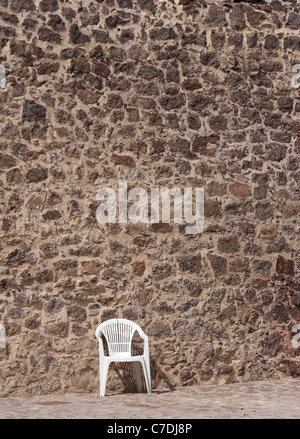 stoned Stadtmauer mit einem weißen Stuhl Stockfoto