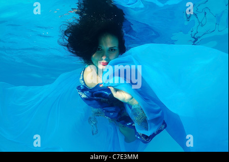 Eine junge Frau mit großen Haar posiert in einem Pool unter Wasser Stockfoto