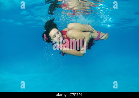 Eine junge Frau mit großen Haar posiert in einem Pool unter Wasser Stockfoto