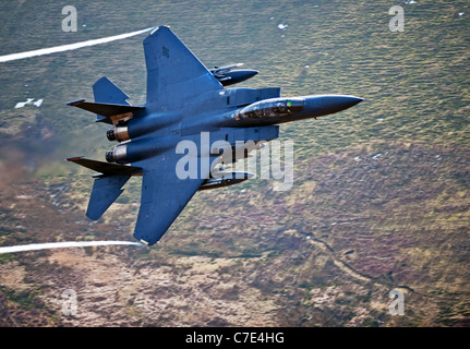 USAF F-15E Strike Eagle macht eine Drehung bei einem niedrig fliegenden Flug in mid Wales erschossen von der Bergseite Stockfoto