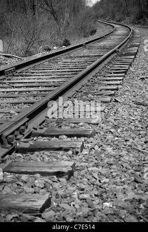 Eisenbahnschienen biegen ab in die Ferne Zukunft - schwarz / weiß Stockfoto