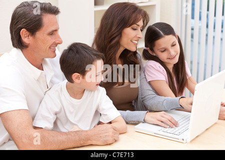 Eine attraktive, Familienglück von Mutter, Vater, Sohn und Tochter sitzen am Tisch zu Hause Spaß mit einem Laptopcomputer Stockfoto