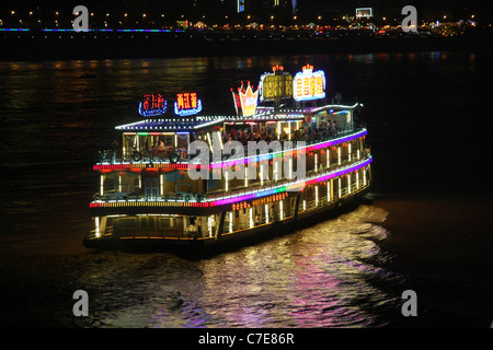 Nachtaufnahme von einem gut beleuchteten Dinner cruise Boot am Jangtse-Fluss in Chongqing, China Stockfoto