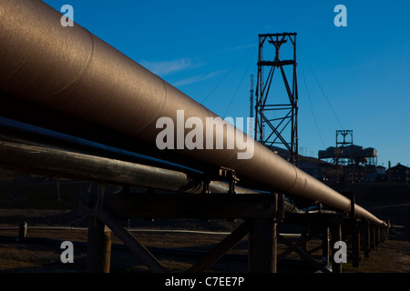 Thermische Heizungsrohre in Longyearbyen, Svalbard. Alte Kohle-Bergbau-Maschinen im Hintergrund Stockfoto