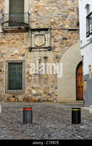 Straße mit Emblem an der Wand und die Barriere in Cáceres (Extremadura, Spanien) Stockfoto