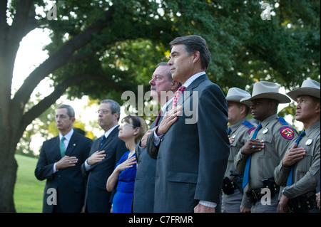 Texas-Gouverneur Rick Perry und andere Gäste begrüssen die amerikanische Flagge mit Händen über Herzen an einer Gedenkfeier für 9/11 Angriffe Stockfoto