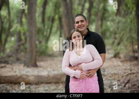 Happy Young verheiratet paar stehen im Wald, eingehüllt in die Arme, lächelnd in die Kamera. Stockfoto