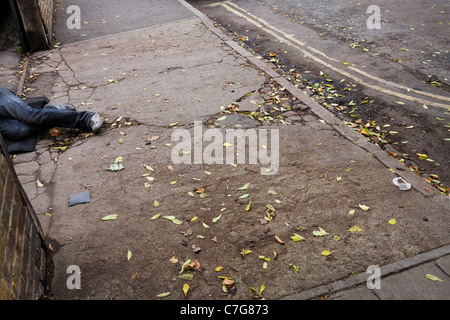 Ein paar Beine liegen seltsam am Eingang einer Auffahrt auf einer Londoner Straße. Stockfoto