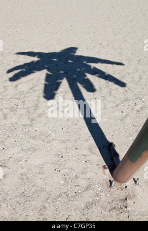 Eine Person neben einer gefälschten Palme, Fokus auf Schatten Stockfoto