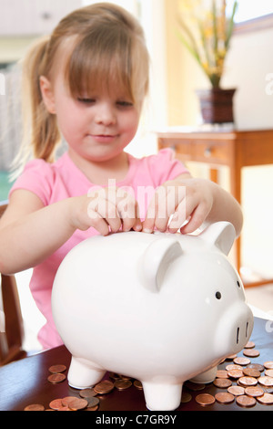 Ein Mädchen, Münzen in ein Sparschwein Stockfoto