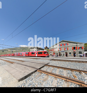 Zug der Rhätische Bahn Ankunft am Bahnhof Ospizio Bernina auf dem Berninapass. Schweiz. Stockfoto