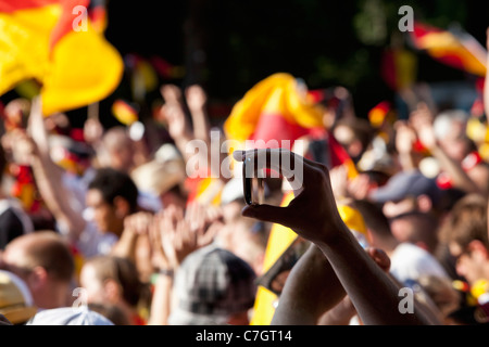 Detail einer Person in einer Menschenmenge halten eines Handys Stockfoto