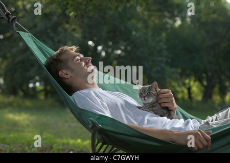 Ein Mann liegen in der Hängematte eine Katze streicheln Stockfoto