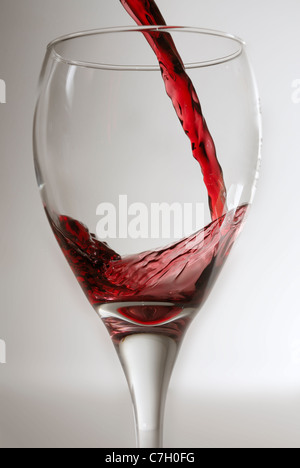 Rotwein in ein sauberes Weinglas gegen einen grauen Hintergrund. Stockfoto
