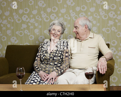 Älteres Paar entspannt auf Couch mit zwei Gläser Wein auf dem Tisch Stockfoto