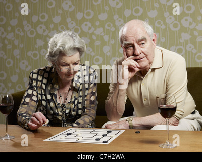 Älteres Paar spielen Muehles und Mann sieht ungeduldig Stockfoto