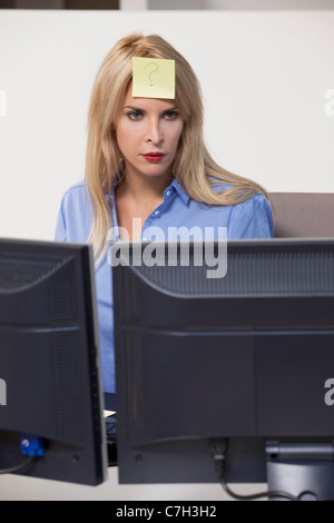 Frau starrte auf Computer mit Klebstoff Hinweis auf der Stirn Stockfoto
