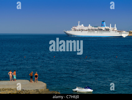 Das Kreuzfahrtschiff Thomson Spirit verlassen den Hafen von Agios Nikolaos auf der griechischen Insel Kreta von Urlaubern beobachtet. Stockfoto