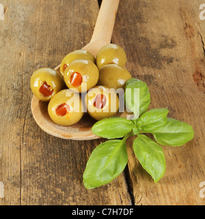 Oliven und Basilikum in einem Holzlöffel auf alte verwitterte Holz Stockfoto