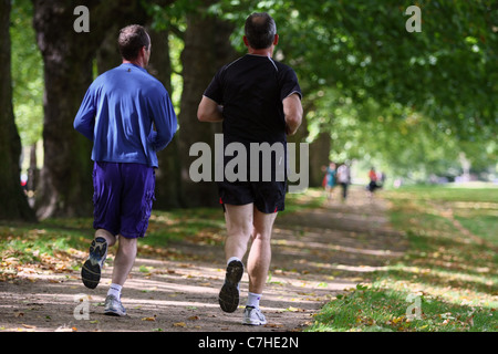 Zwei männliche Jogger Joggen im St James Park, London, zur Mittagszeit an einem Wochentag Stockfoto