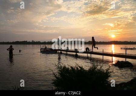 Menschen spielen ich See und auf einem Steg mit Sonnenuntergang Stockfoto