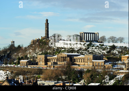 Calton Hill im Schnee mit den alten Royal High School Gebäude im Vordergrund von Salisbury Crags, Edinburgh, Schottland Stockfoto