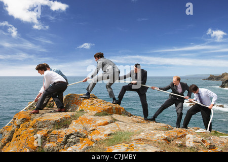 Geschäftsleute ziehen Seil über Klippe Stockfoto