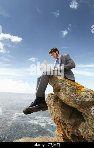 Geschäftsmann mit Laptop auf Klippe Stockfoto