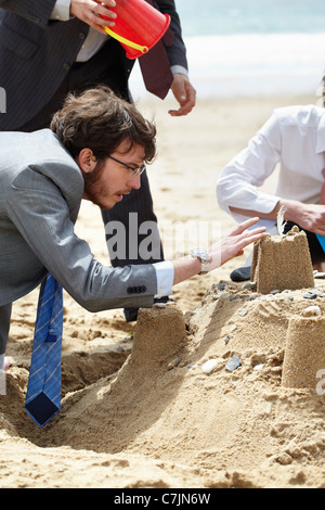 Geschäftsleute, die Sandburg bauen Stockfoto